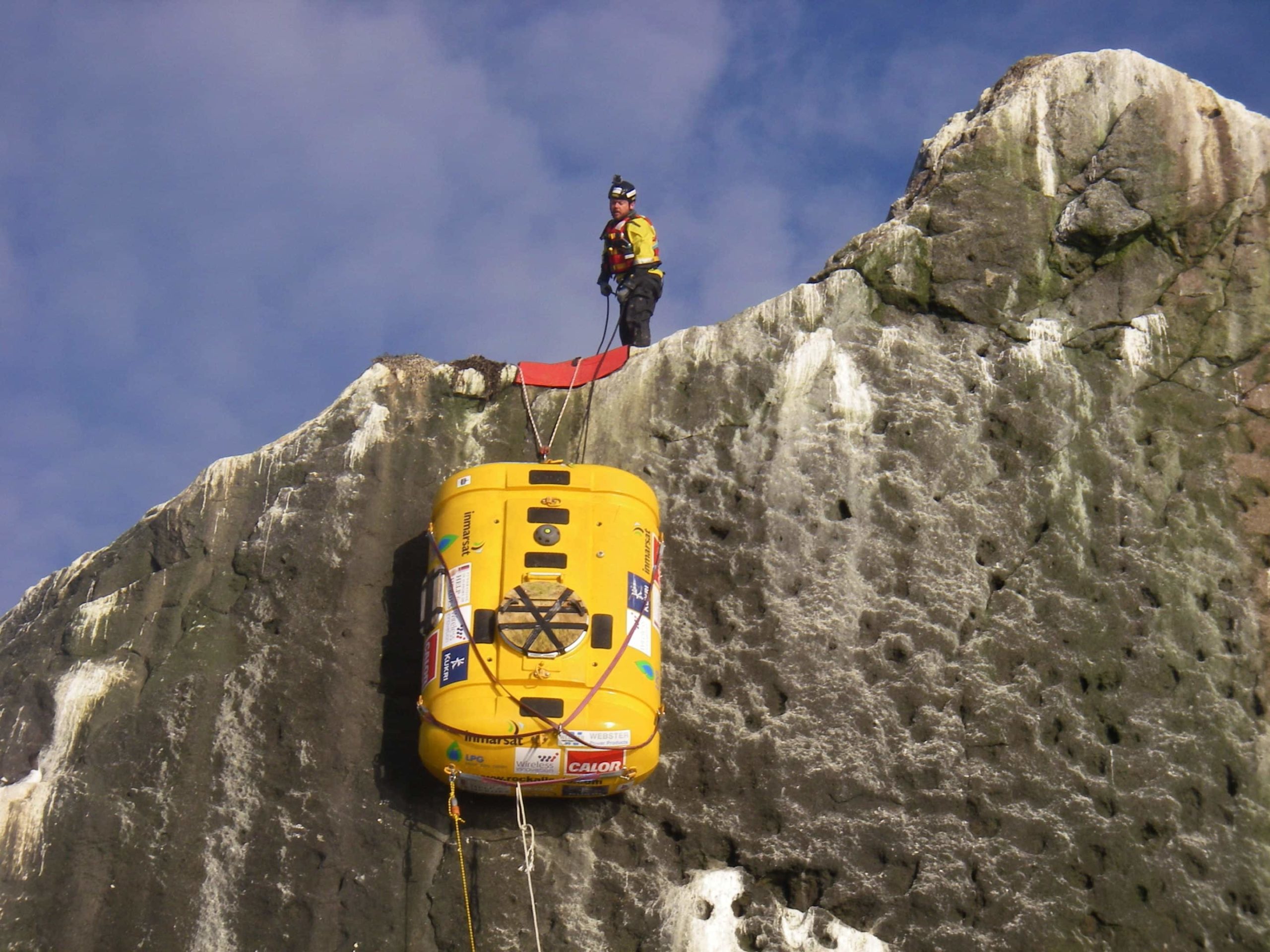 Person rescuing yellow submarine from cliff.