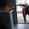 Man extinguishing bin fire with extinguisher.