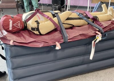 Rescue dummy strapped on inflatable medical stretcher using Patient Handling Training Manikins