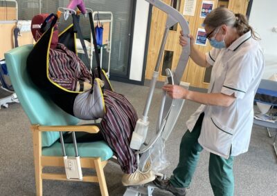 Caregiver using lifting device to assist patient - using Patient Handling Training Manikin