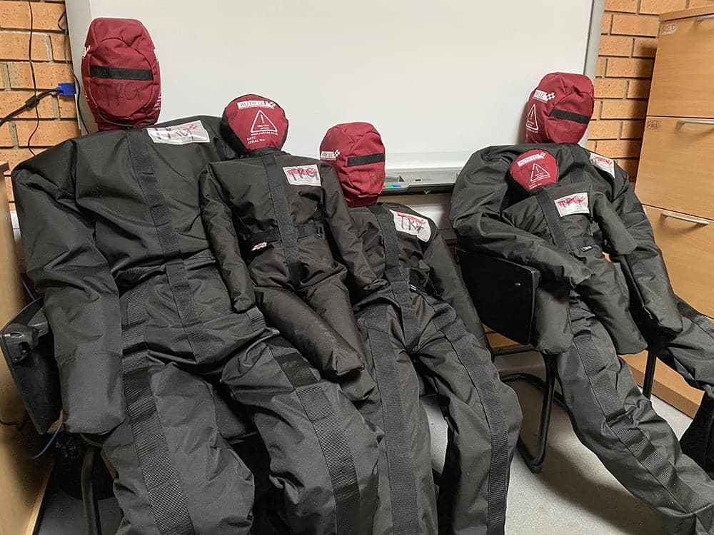 Rescue training mannequins in different sizes on chairs.