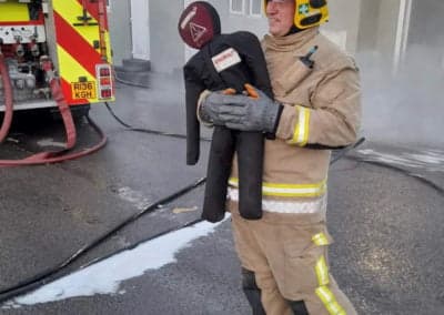 Fire fighter holding child duty training manikin in fire rescue practice