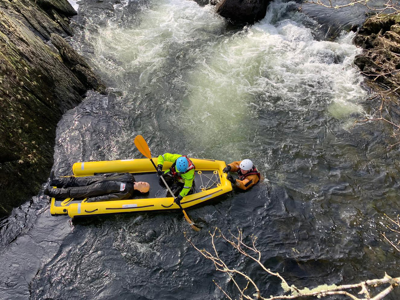 Rescue team assisting person in a river raft - using advanced water rescue manikin