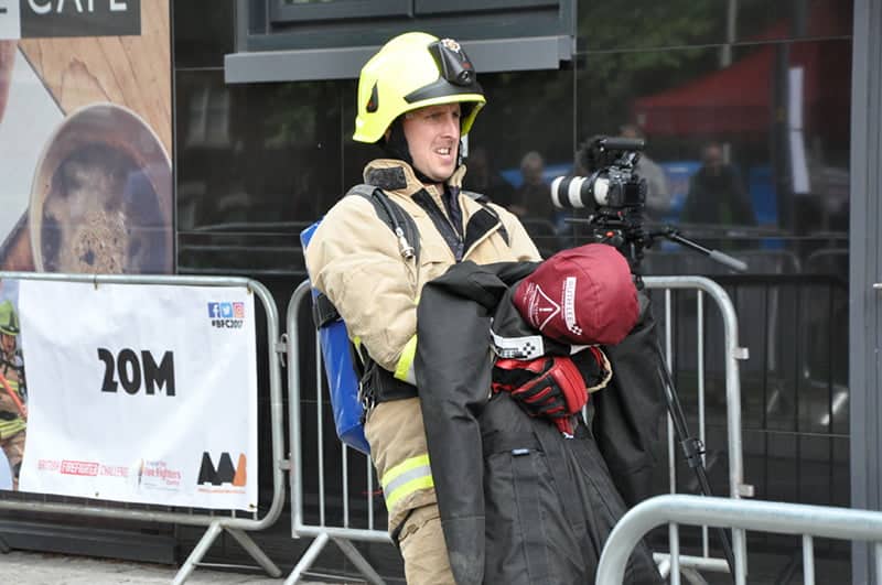 Firefighter training in uniform standing by a camera setup.
