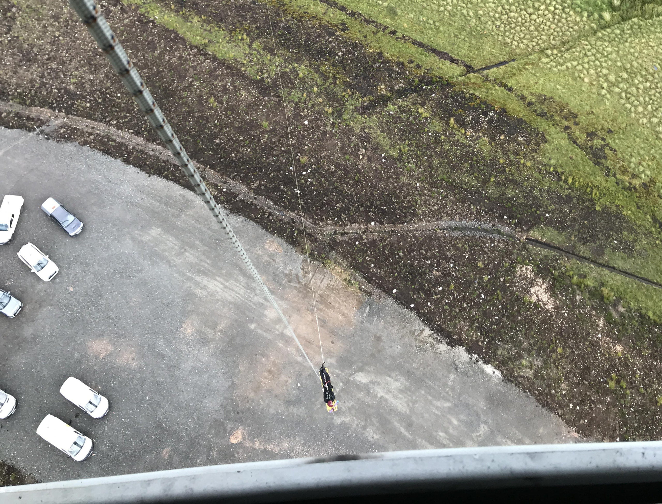 Person abseiling from tall wind turbine structure, viewed from above.