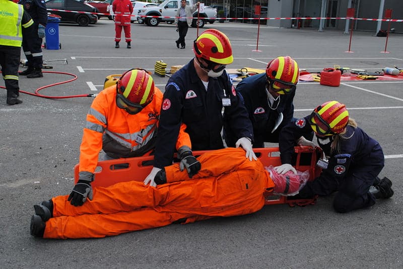 Rescuers securing an injured person manikin on a stretcher.