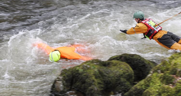 Rescue worker attempts to save person in river.