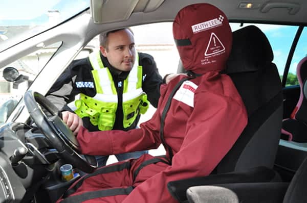 Police officer inspecting car crash manikin. Creating realistic and challenging extrication exercises with manikins.