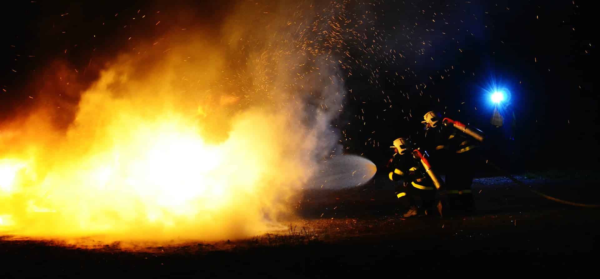 Firefighters extinguishing a large blaze at night.
