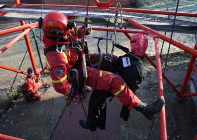 Firefighters in training exercise, using rescue harness and equipment.