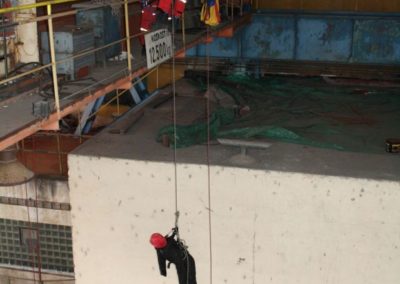 Rescue team practising high-angle rope skills indoors.