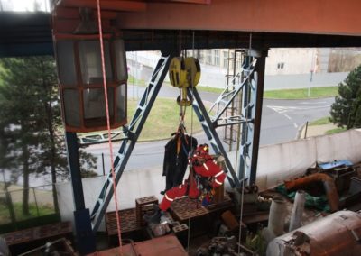 Rescue training exercise with crane and worker in harness.