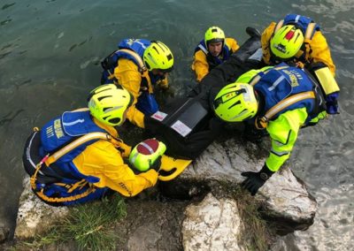 Rescue team assisting person at lake shore.