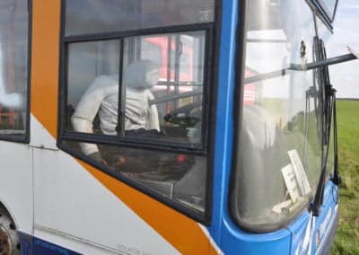 Multi Trauma Training Manikins - Abandoned bus with a mannequin inside, parked in field.
