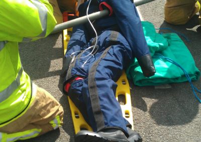 Emergency responders assisting injured individual on stretcher.