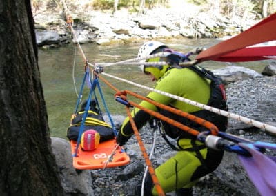 Rescue team securing stretcher over a river in forest.