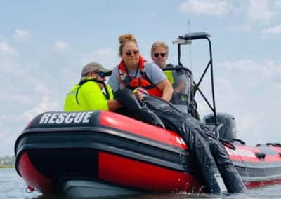 Rescue team assisting in red inflatable boat on water.