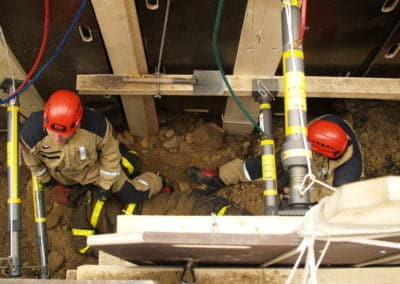 Rescue workers assisting person in trench.