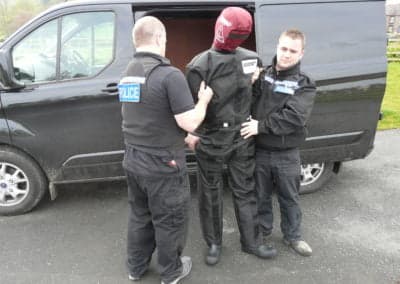 Police officers training with a practice dummy.