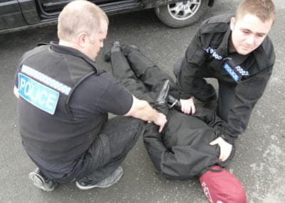 Police officers detaining a person manikin on the ground.