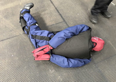 Person restrained on the ground during training exercise.
