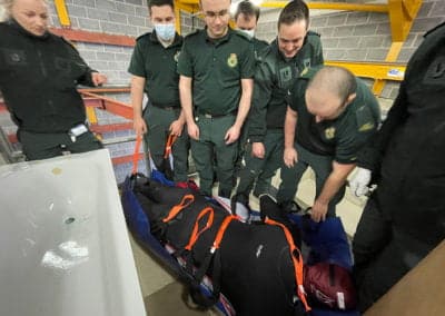 Paramedics securing a patient on a stretcher.