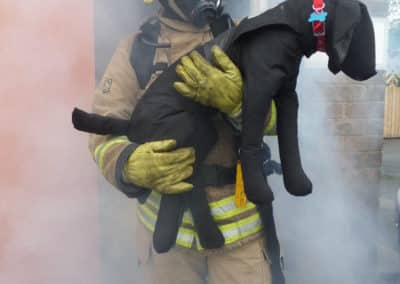 Firefighter rescues a dog from a smoke-filled building.