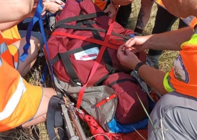 Rescue team securing a stretcher in a field.