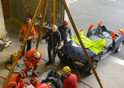 Rescue team training with car in garage setting.