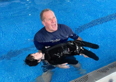 Swim instructor training with a dummy in pool.