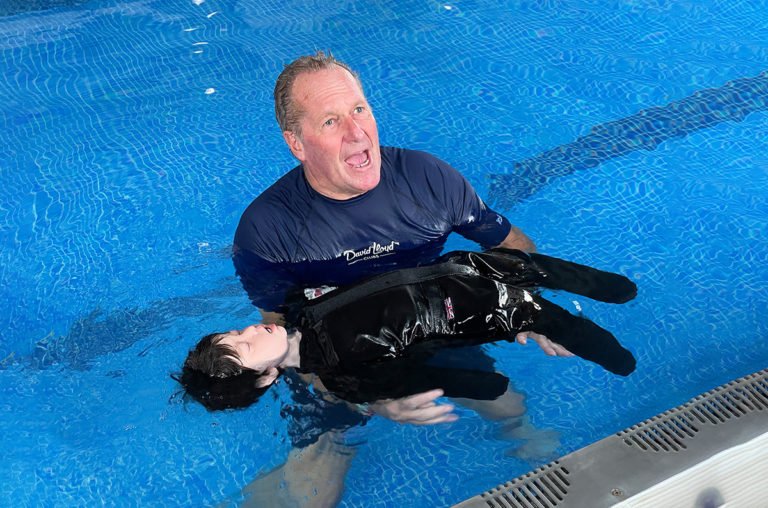 Swim instructor training with a dummy in pool.