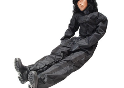 Lifelike training dummy in black suit laying down.