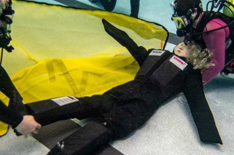 Scuba divers practice underwater rescue with training mannequin.