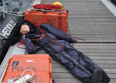 Rescue training dummy on dock beside police equipment.