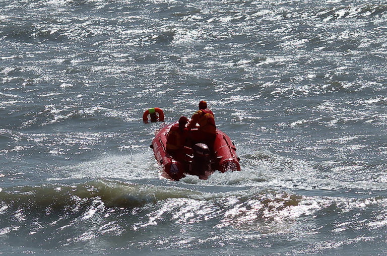 Rescue boat in wavy sea locating a floating ring.