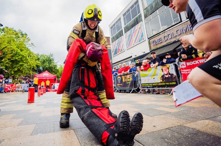 Firefighter competition event with crowd watching demonstration.