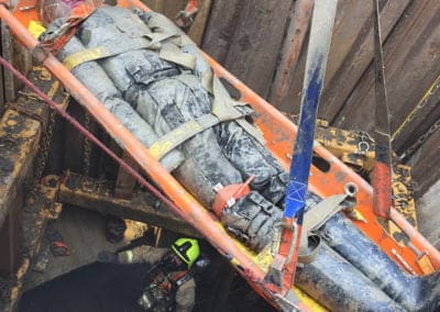 Rescue workers lift injured person from construction site pit.