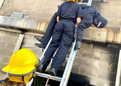 Firefighters in training performing a ladder rescue.