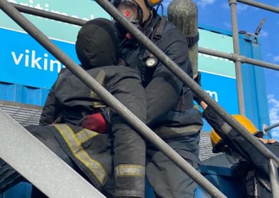 Firefighters practicing rescue on metal stairs.