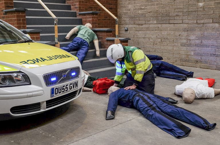 Paramedic training exercise with dummies and ambulance.