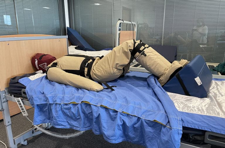 Medical dummy lying on hospital bed for training purposes.