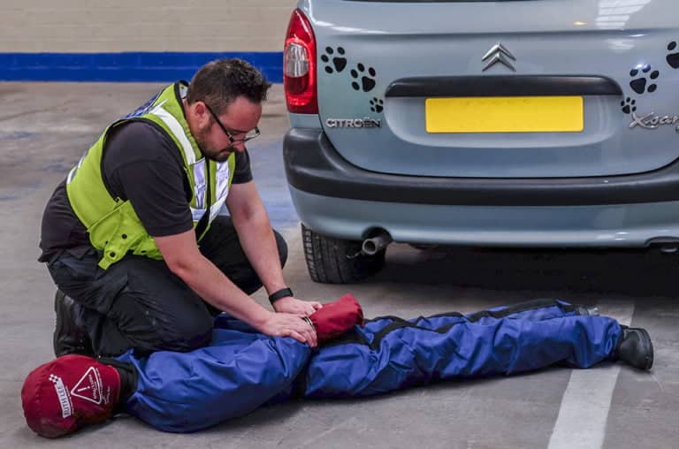 First aid training: man performing CPR on dummy.