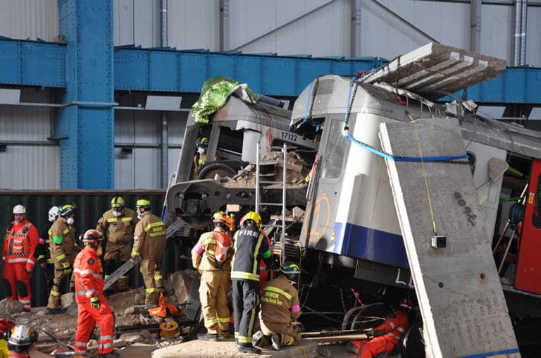 Emergency responders attend train crash scene indoors.