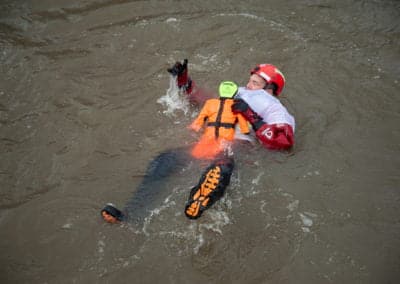 Rescue worker training in river with dummy.