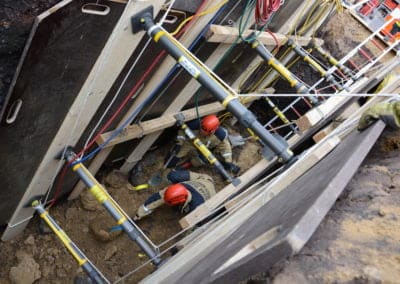 Rescue workers excavating a trench securely supported by shoring.