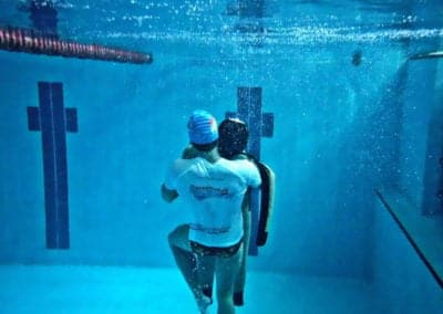 Swim instructor training with manikin underwater in a pool.