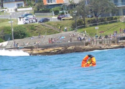Lifeguard training in the ocean near rocky shore.