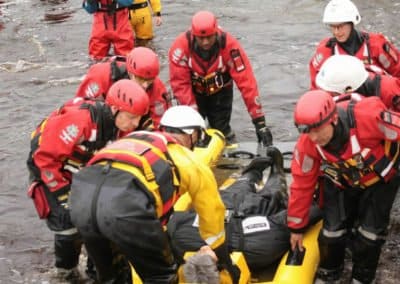 Rescue team saving person from water on inflatable stretcher.