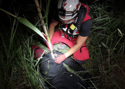 Rescue worker aiding person in outdoor setting at night.