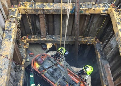 Rescue operation in confined space, firefighters lift injured worker.
